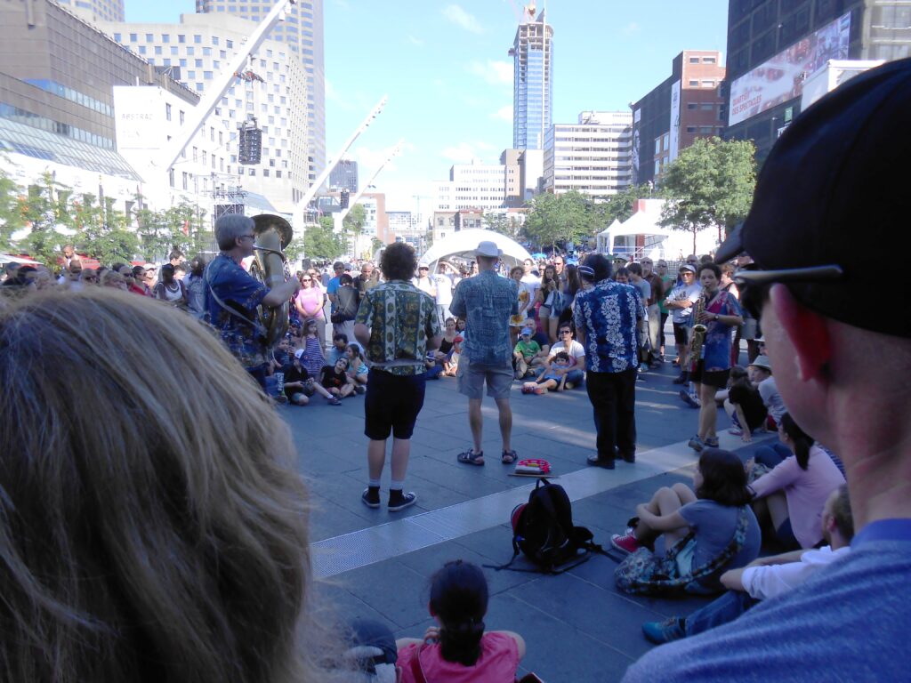 Publiek en straatband op Place des Festivals tijdens FIJM